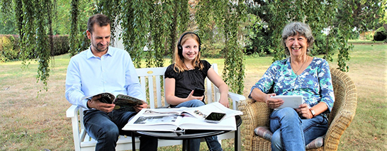 Ein Mann, ein Mädchen und eine Frau sitzen auf einer Gartenbank und lesen&nbsp;&copy;&nbsp;Stadt Hildesheim