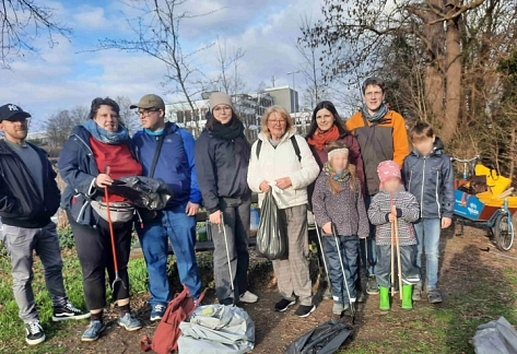 Gruppe mit Kindern und Erwachsenen mit Müllzangen und Säcken voller Müll am Liebesgrund