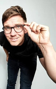 Quizmaster Tom Zimmermann beugt sich vor und schaut durch seine Brille in die Kamera.&nbsp;&copy;&nbsp;Tom&Darren