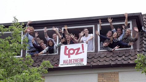 Das Team des TPZ winkt aus einem Fenster. © TPZ-Team_Foto: Chris Gossmann