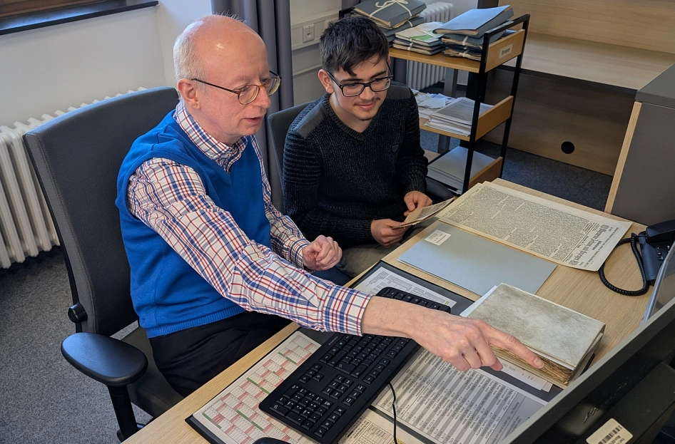 Archivmitarbeiter Harald Braem zeigt Hisham Hadi Omer die Arbeit mit historische Zeitungen.